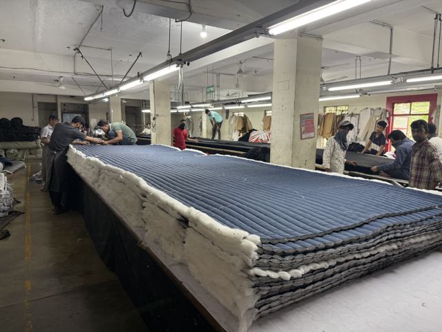 Skilled operators carefully layer and prepare fabric panels for precise cutting on our production floor.