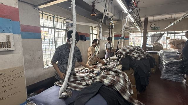 Skilled workers meticulously iron woven garments to ensure a flawless finish in our production facility.